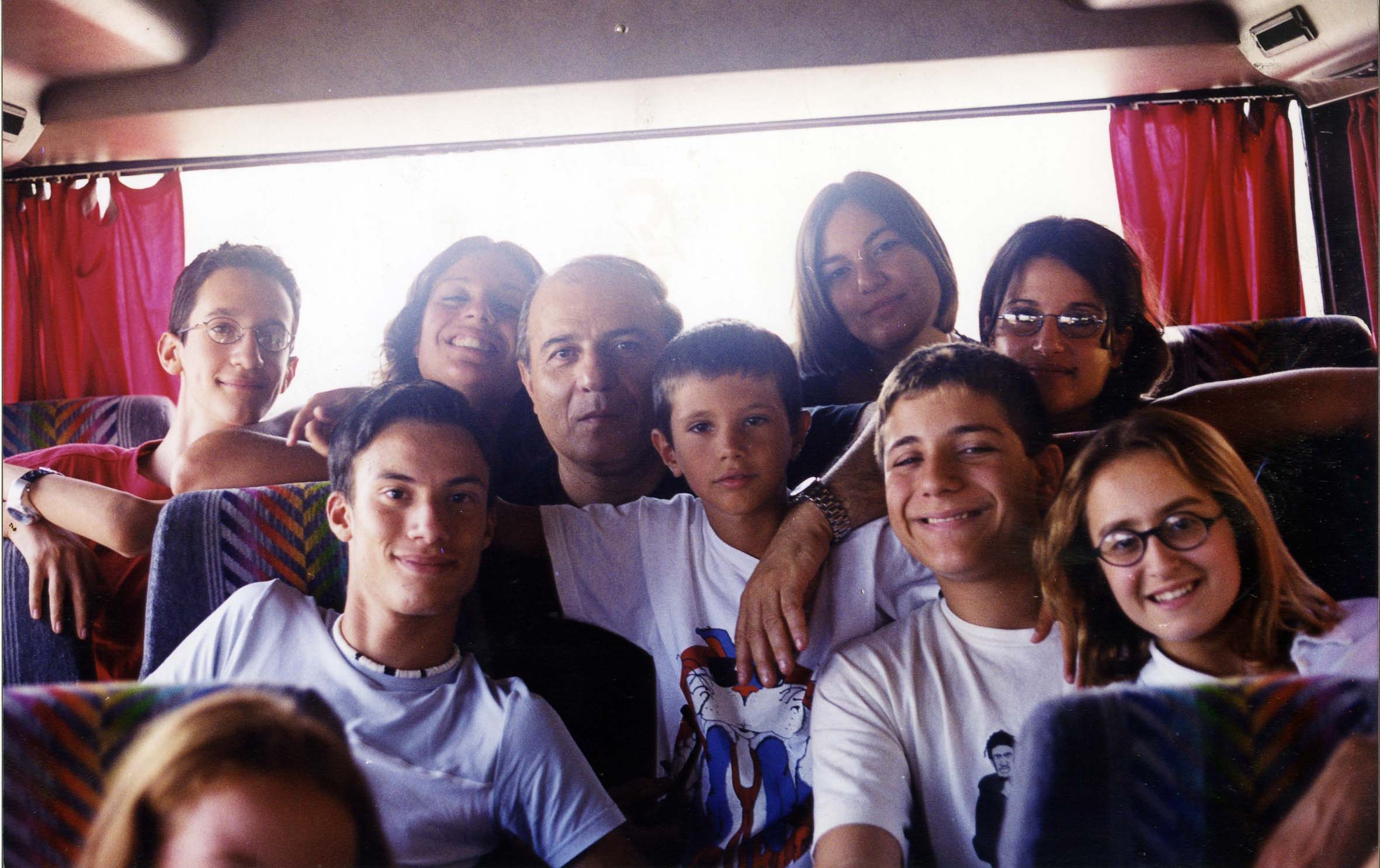 Un gruppo di bambini e adulti fotografato all’interno di un pullman.